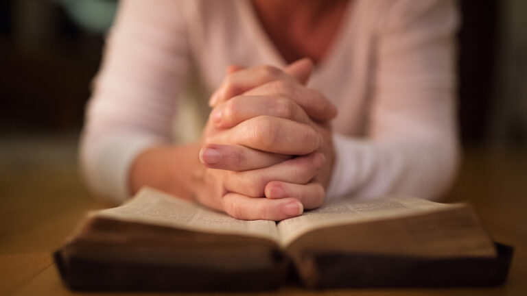 Woman's hands praying over a bible
