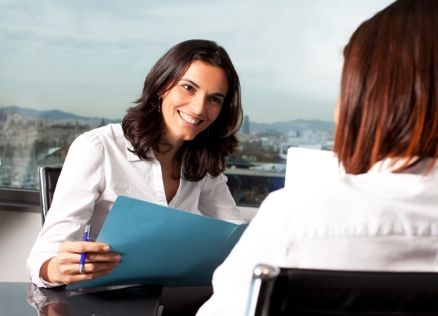 A smiling woman conducting a job interview with a candidate