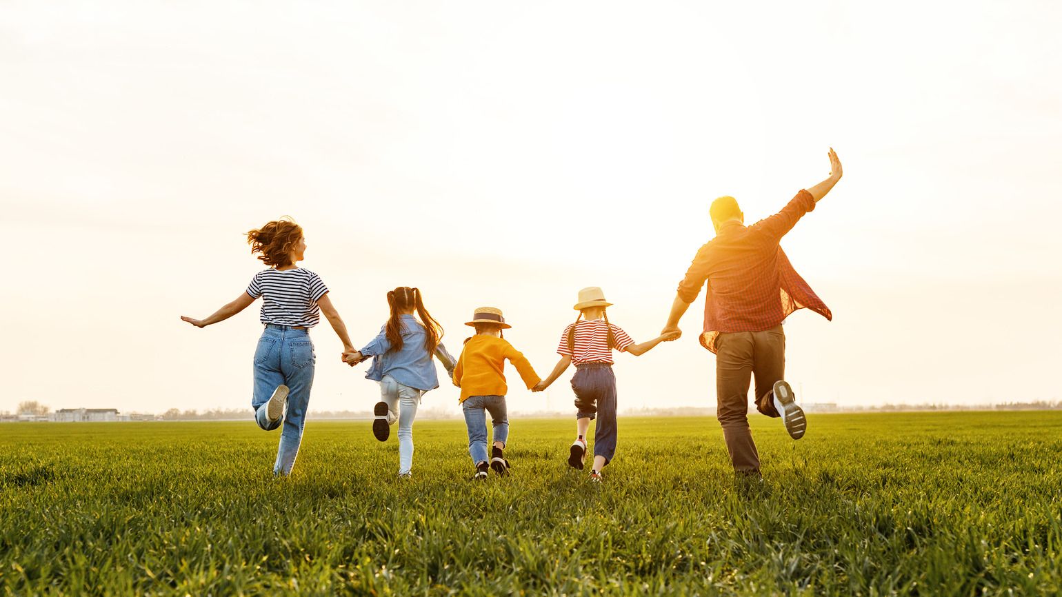 Family running through green field (Getty Images)