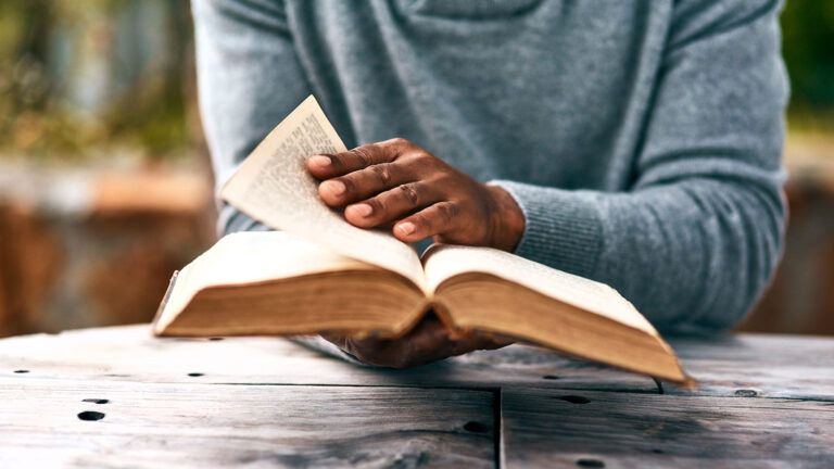 A man's hands holding an open Bible